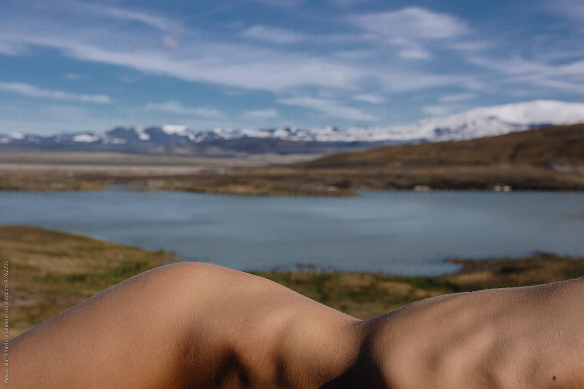 Nude woman lying in front of the lake and snowy mountains in Iceland