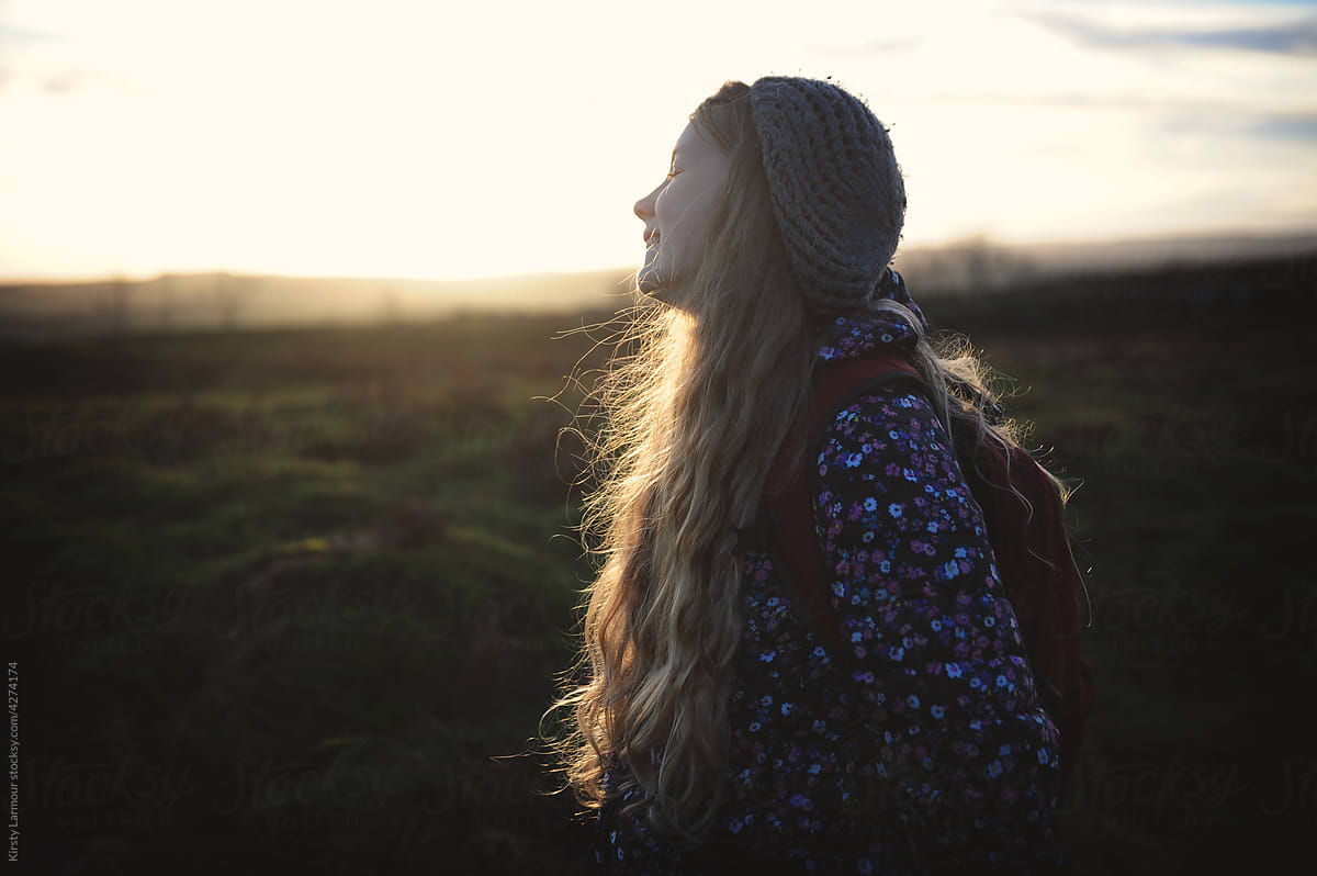 The sun shines through a girls hair on a winters hike