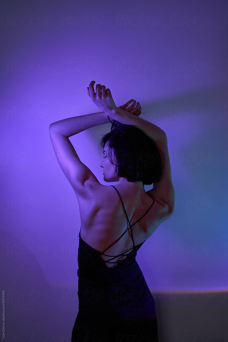 Woman with raised arms under neon illumination