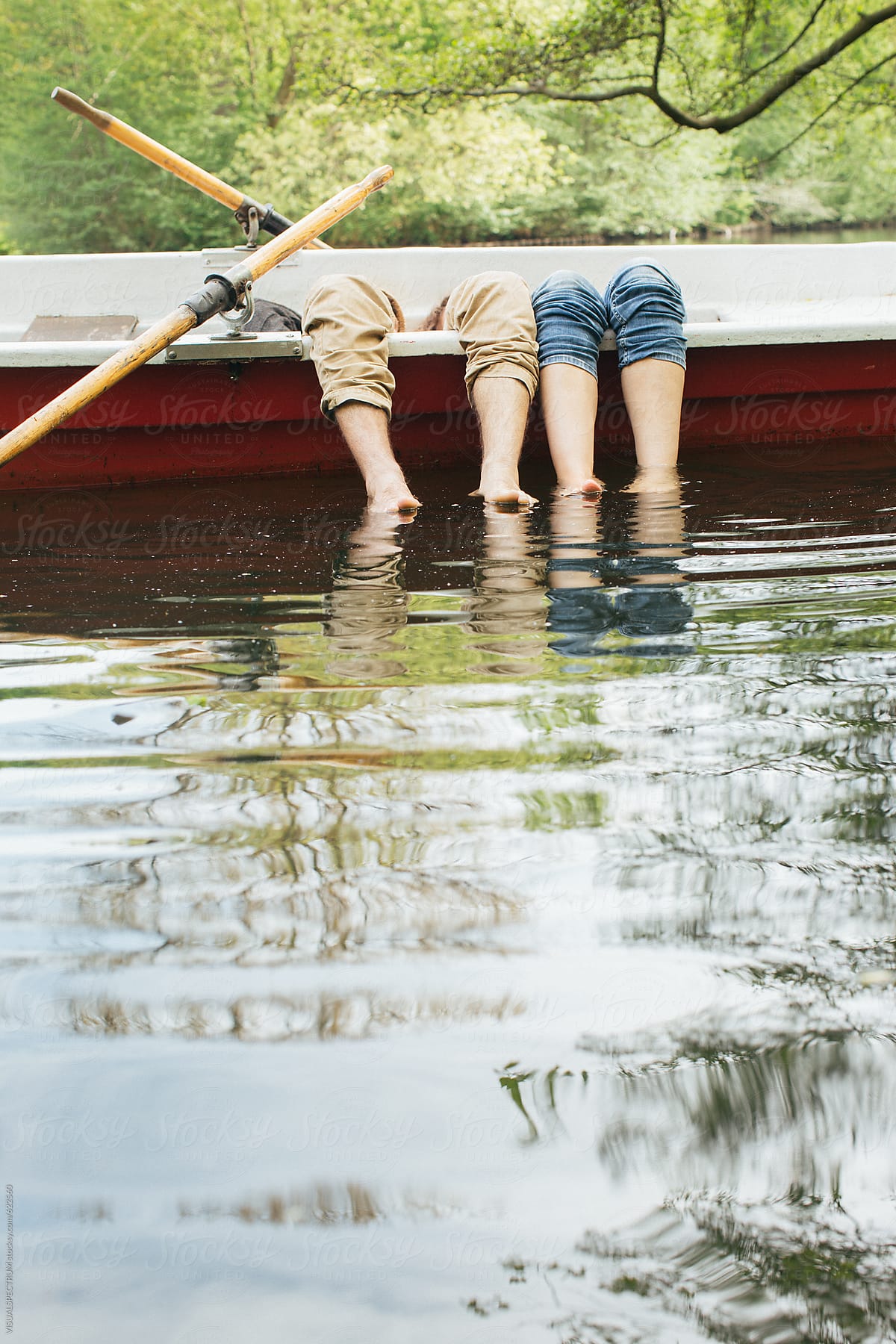 Young Heterosexual Couple Lying in Rowboat and Dipping Feet in Water