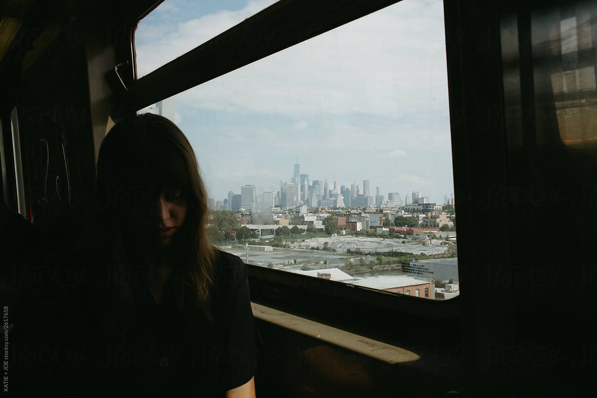 Silhouetted Woman sitting on a subway car with the view of the city in the distance
