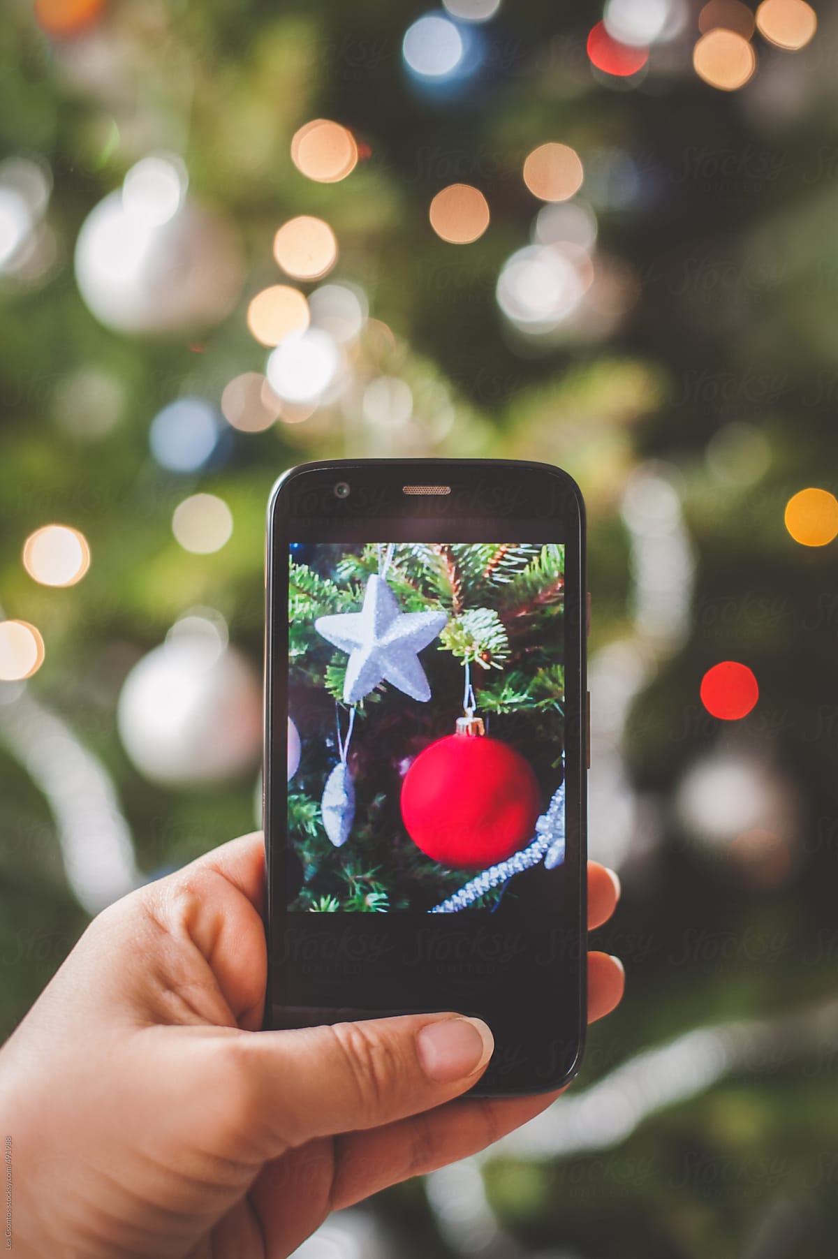 Woman taking a photo of christmas tree ornaments with an Android mobile phone