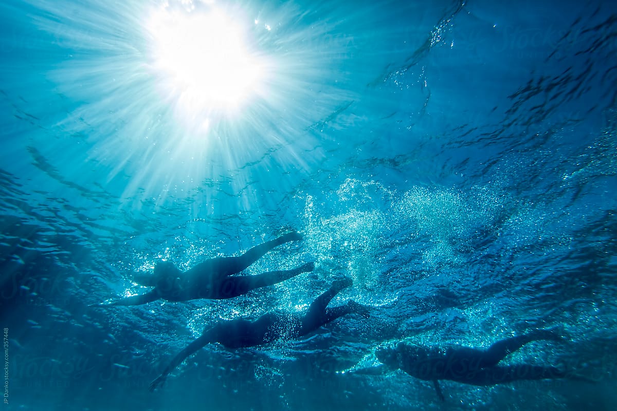 Open Water Triathlon Swimmers Underwater With Sun Flare