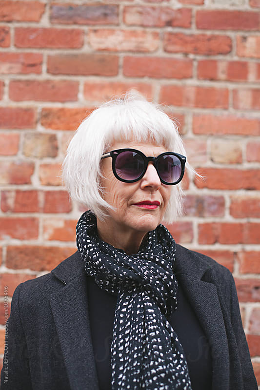 Stylish older woman wearing coat and scarf outdoors