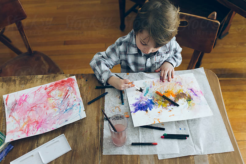 Young boy learning to paint with watercolor crayons