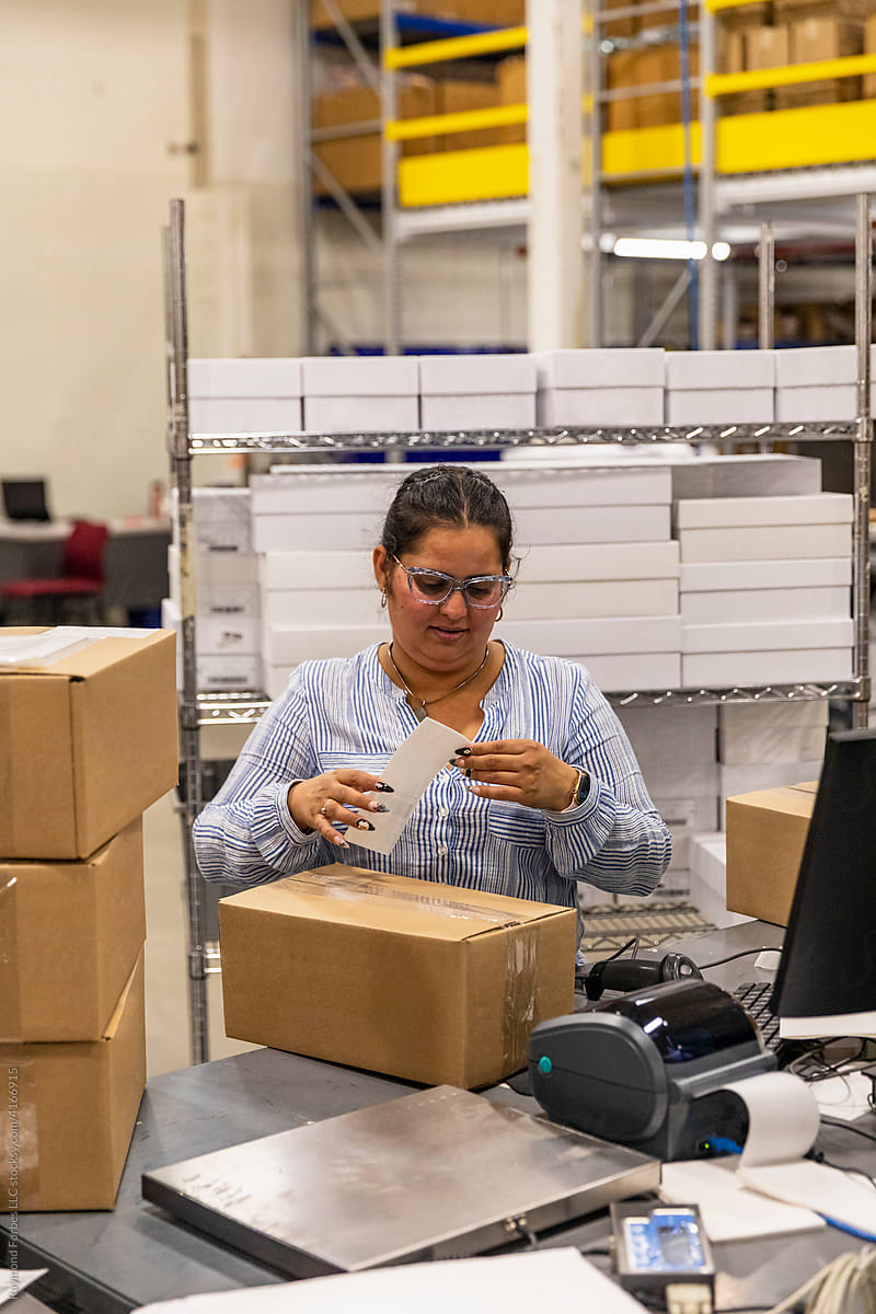 Worker puts shipping label on box  ecommerce warehouse