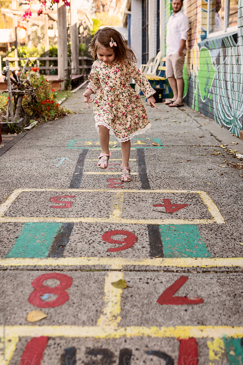 Toddler girl playing hopscotch outside at pre school