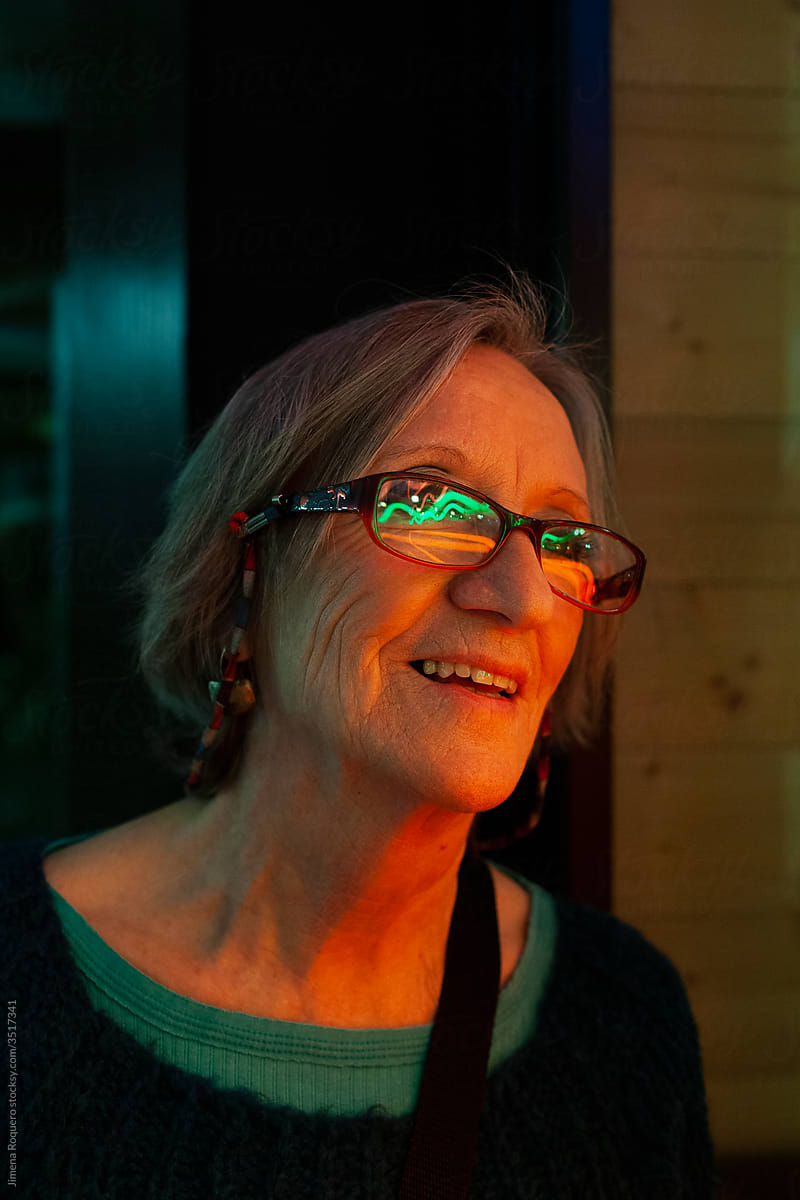 Portrait of elderly woman on neon lights smiling.