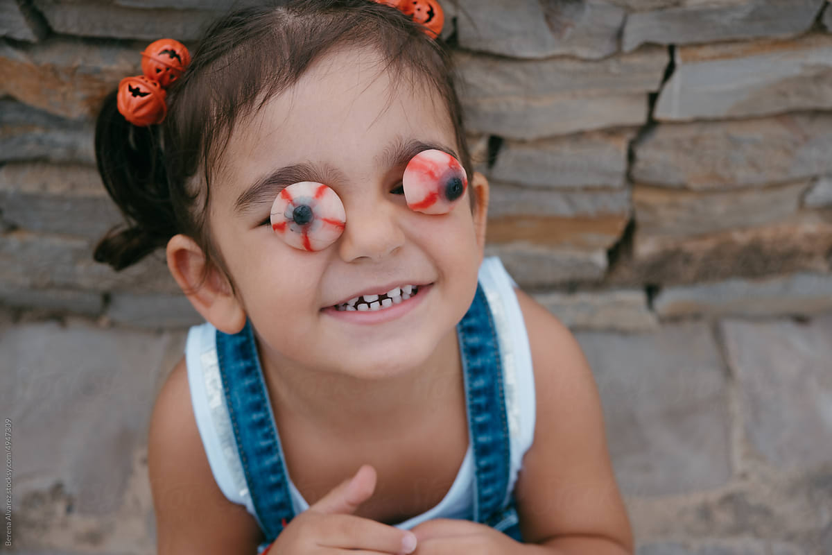 brunette girl with halloween pigtails puts jelly beans on her eyes