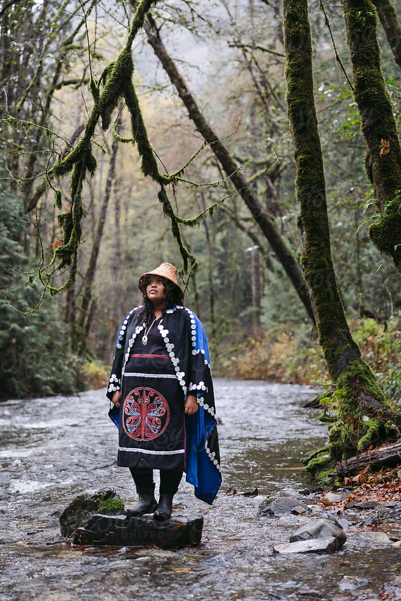 Woman standing near river in ceremony dress.