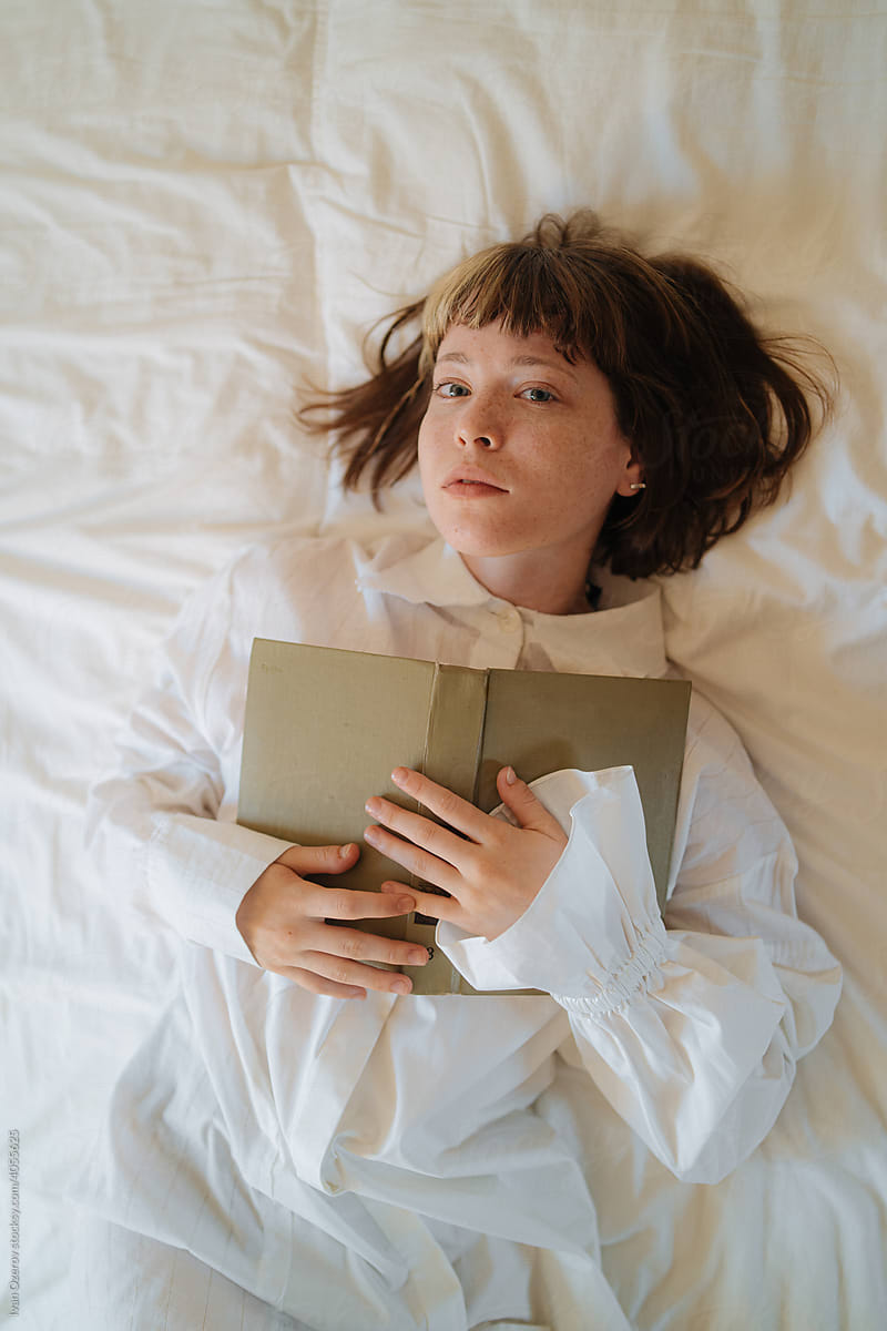 Woman with book lying on bed