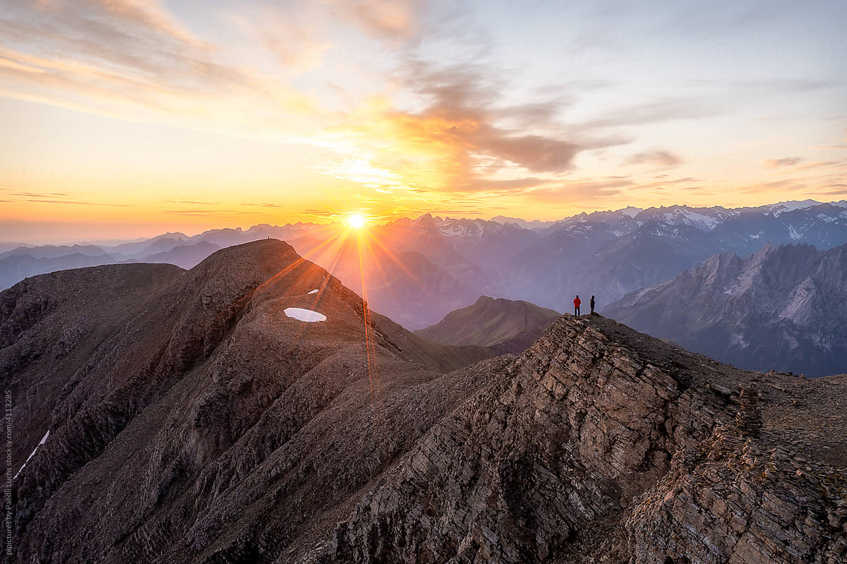 Two people standing on mountain top at sunrise