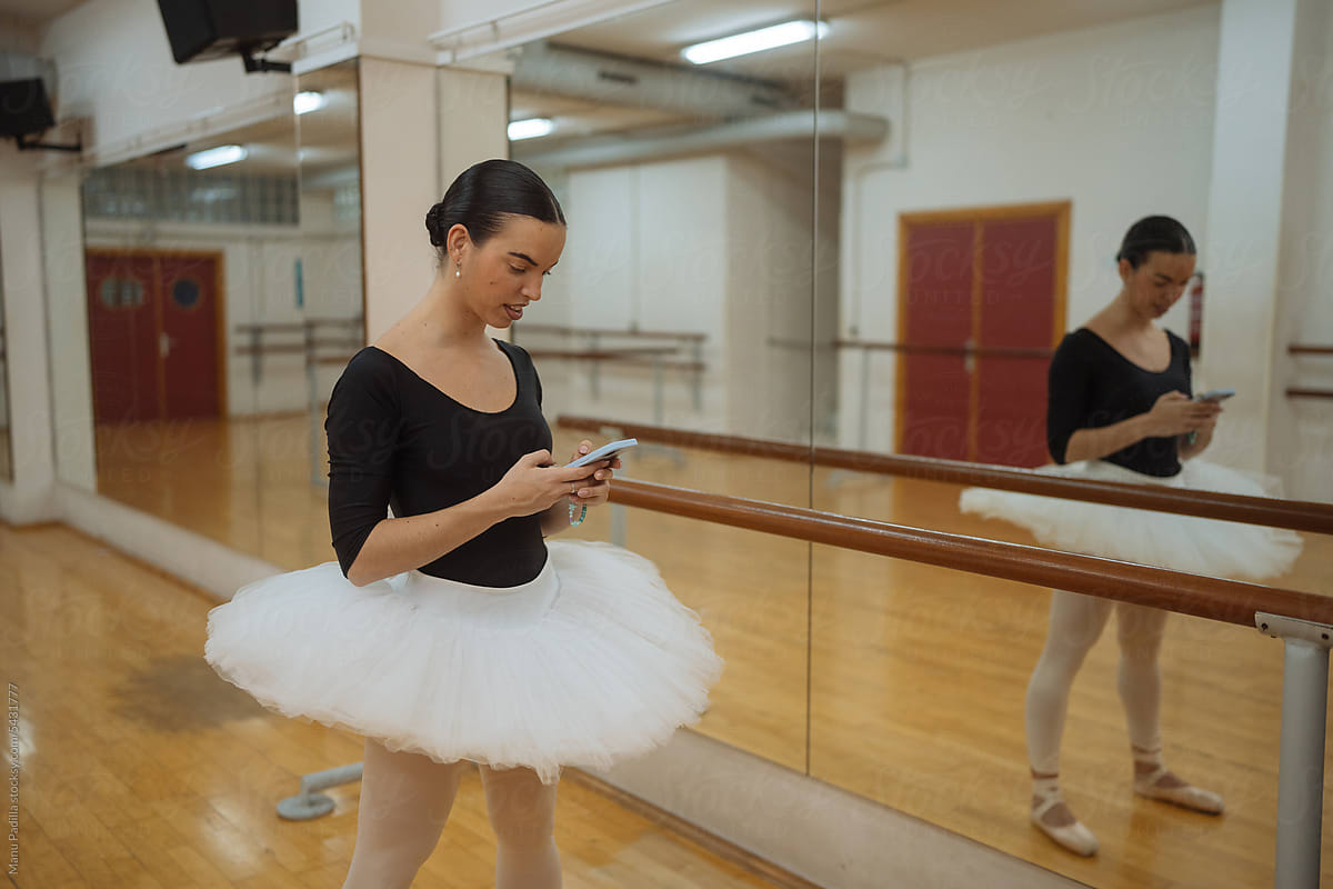 Young ballerina using smartphone in ballet studio