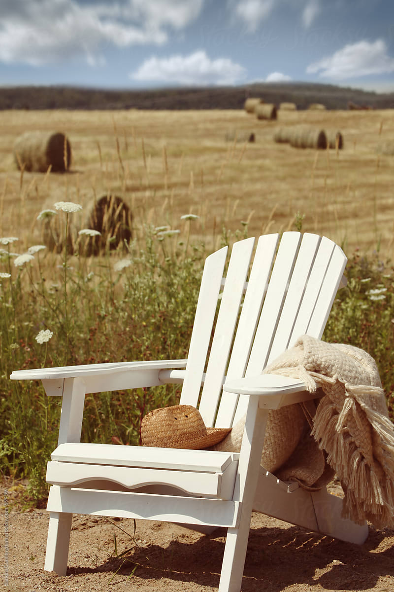 Adirondack chair overlooking bales of hay in field