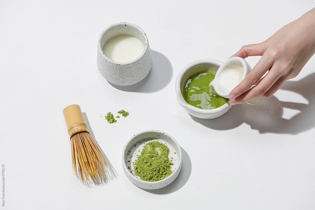 Pouring green matcha into glass on light background