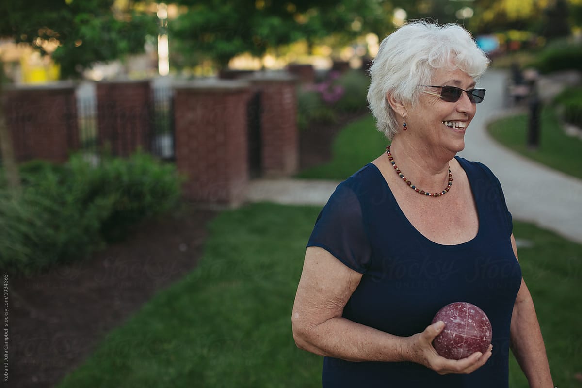 Healthy caucasian senior woman playing fun game of bocce ball outside