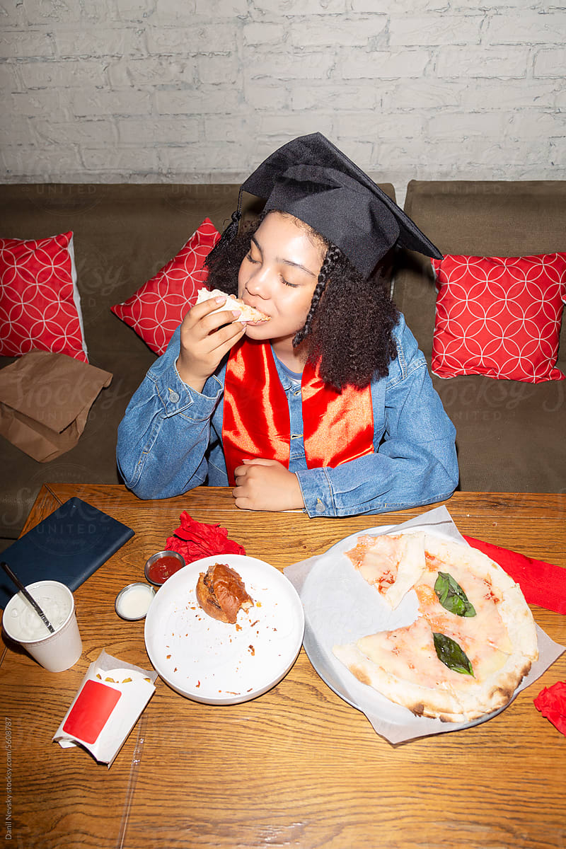 Young black graduate enjoying pizza in restaurant