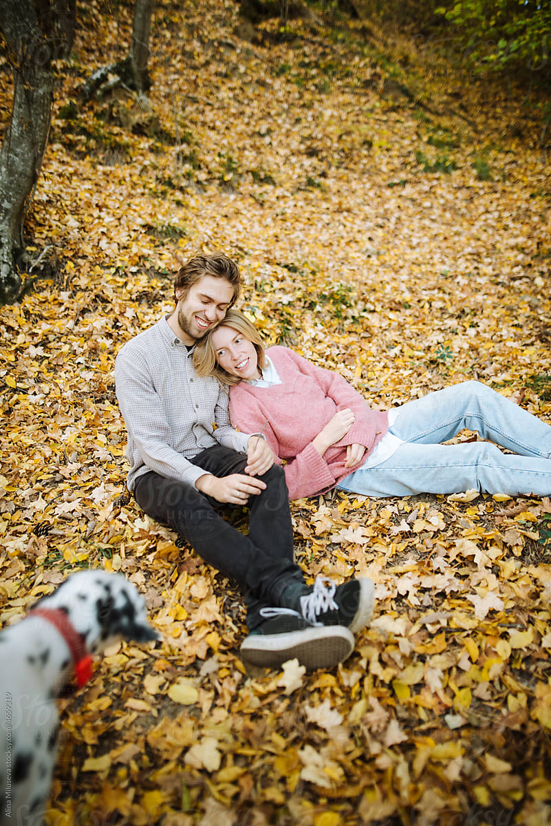Happy couple with dog in autumn forest