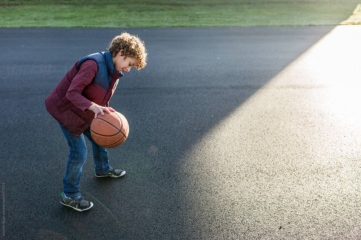 Boy bounces basketball on blacktop