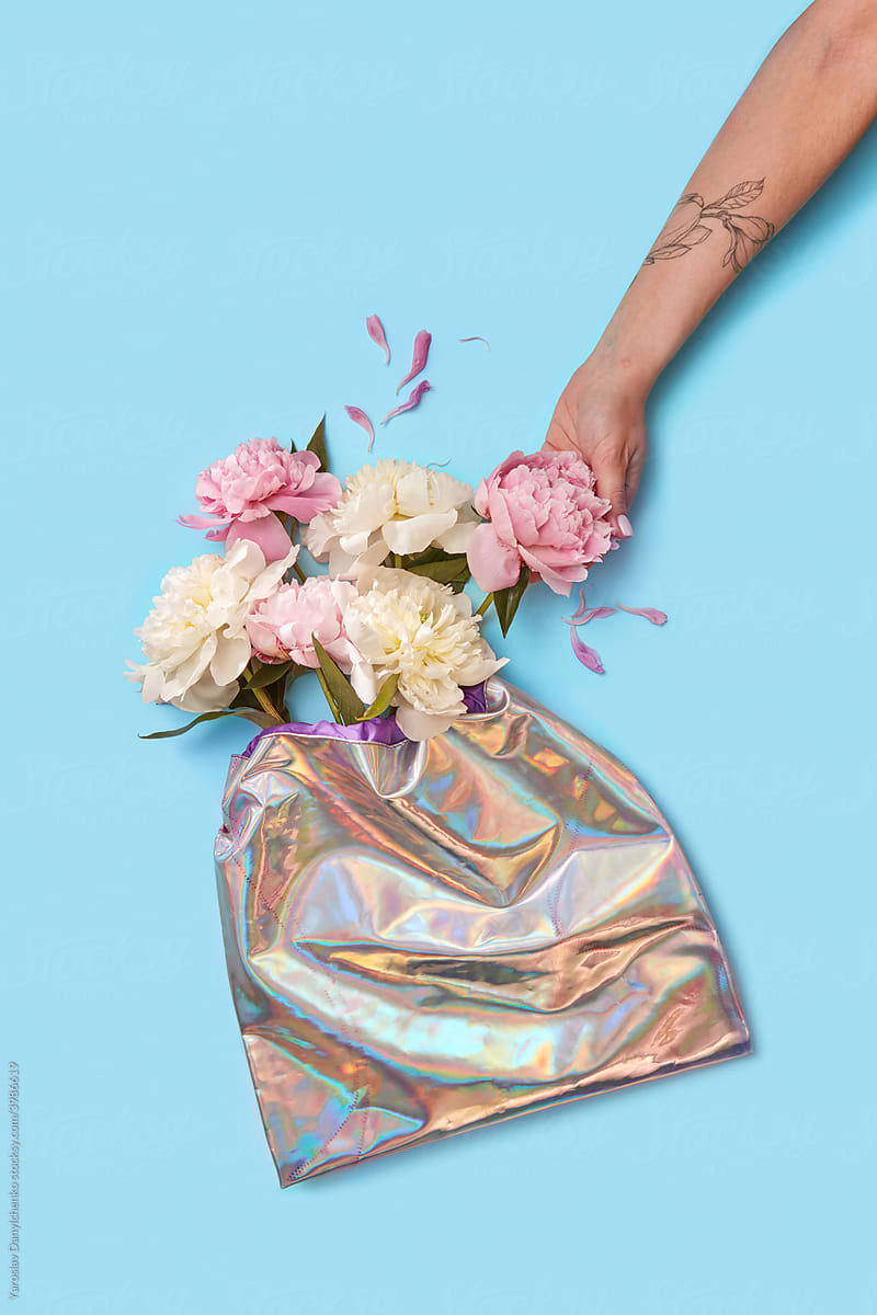 Woman touching peonies in holographic foil bag