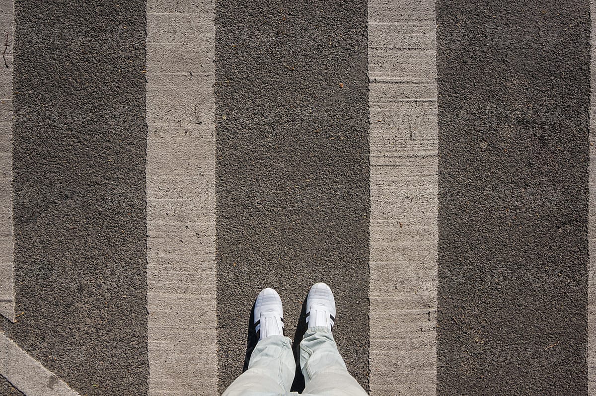 White sneakers between street markings, footsie, personal perspective