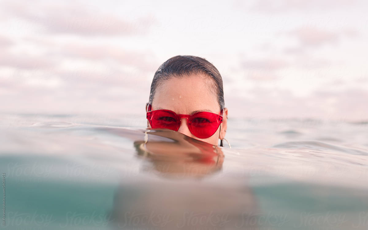 Woman with red sunglasses emerging from the sea