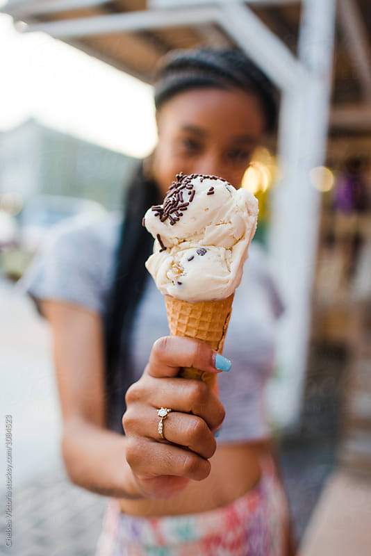 A young woman eating ice cream in the summertime