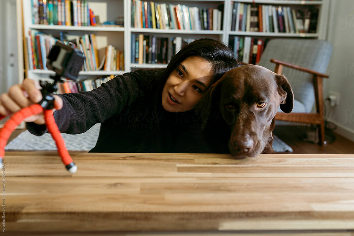 female east asian woman and her labrador dog at home recording a video