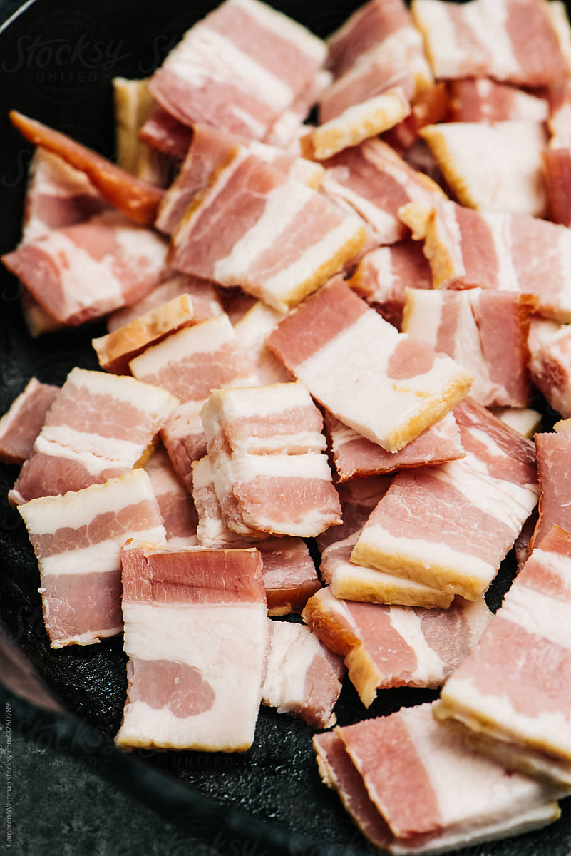 Raw sliced bacon in an iron skillet