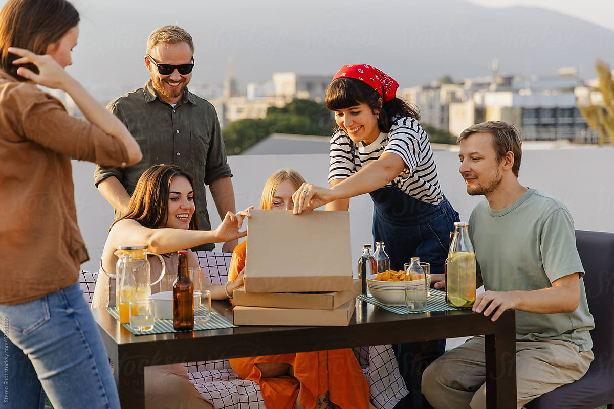 Group of friends eating pizza on rooftop