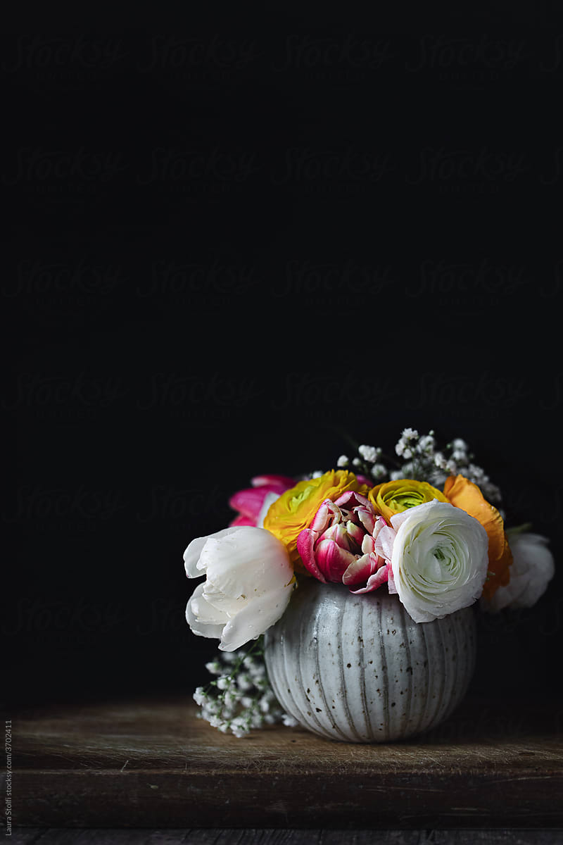Mixed flowers bouquet in vase against black wall