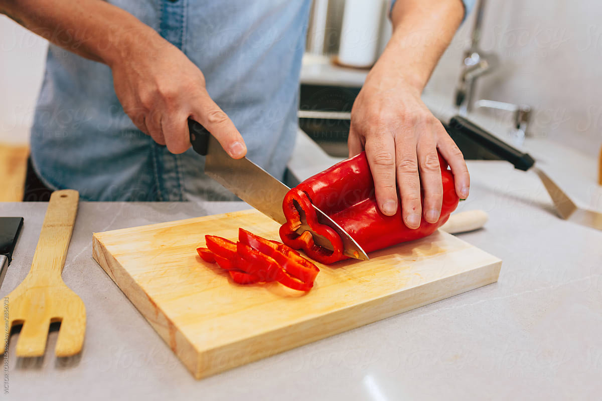 Unrecognizable man cutting peppers in the kitchen