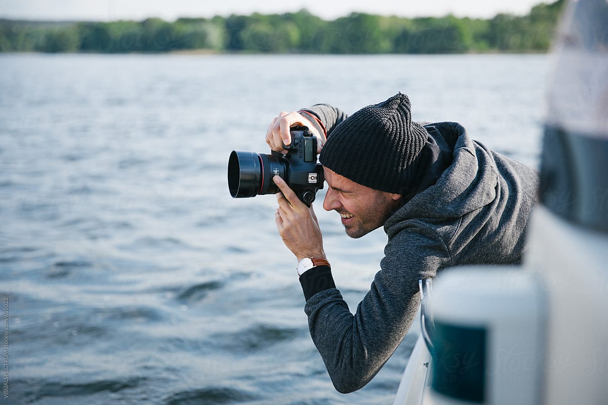 Casually-Dressed Male Photographer Shooting With Digital DSLR Camera on Boat