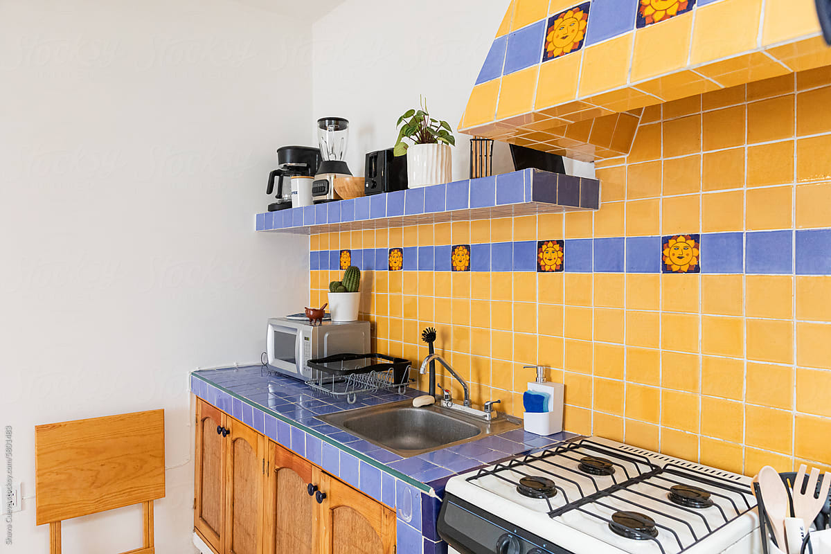 Clean kitchen with blue and yellow tiles next to a stove