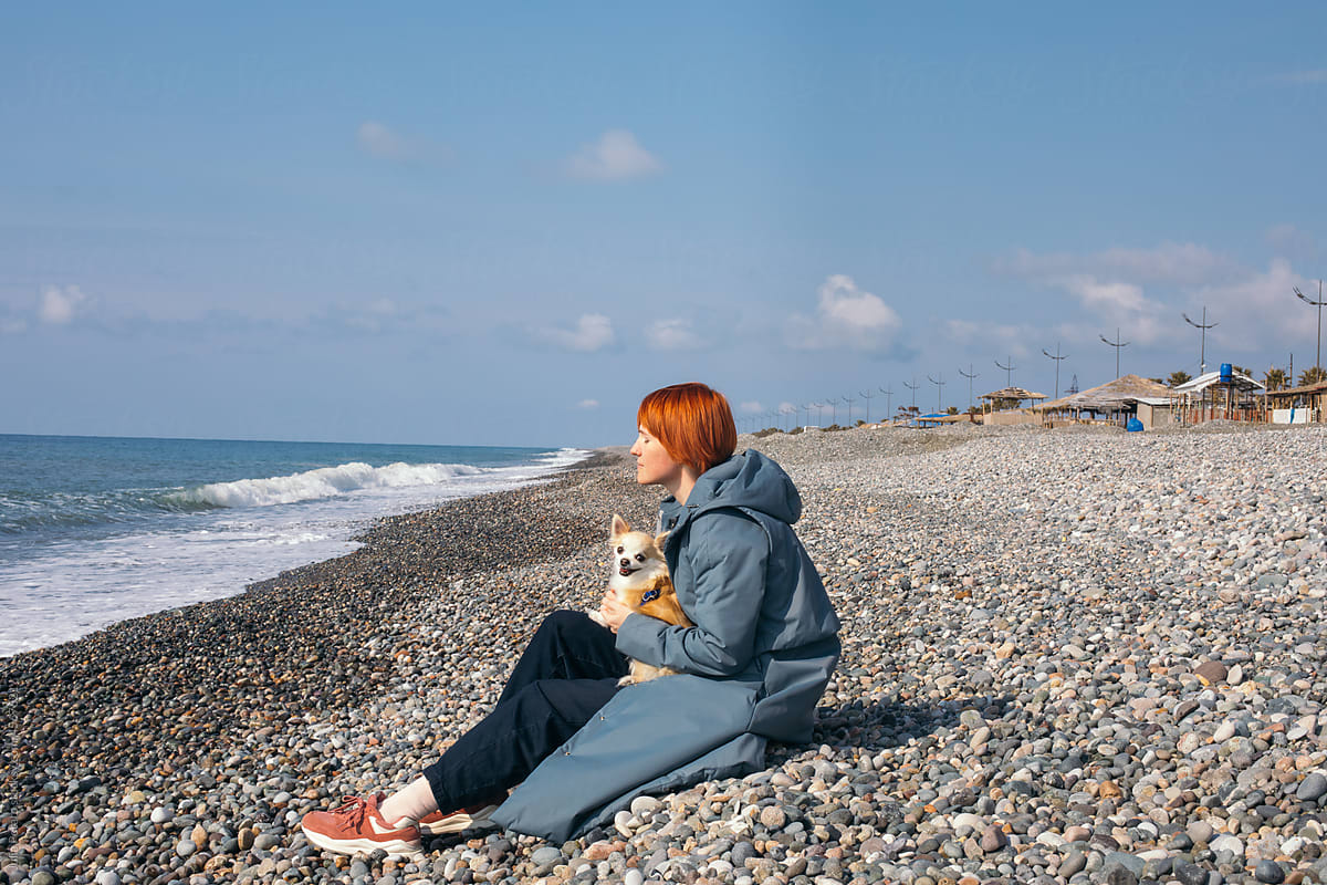 A girl hugs with a dog on the sea beach
