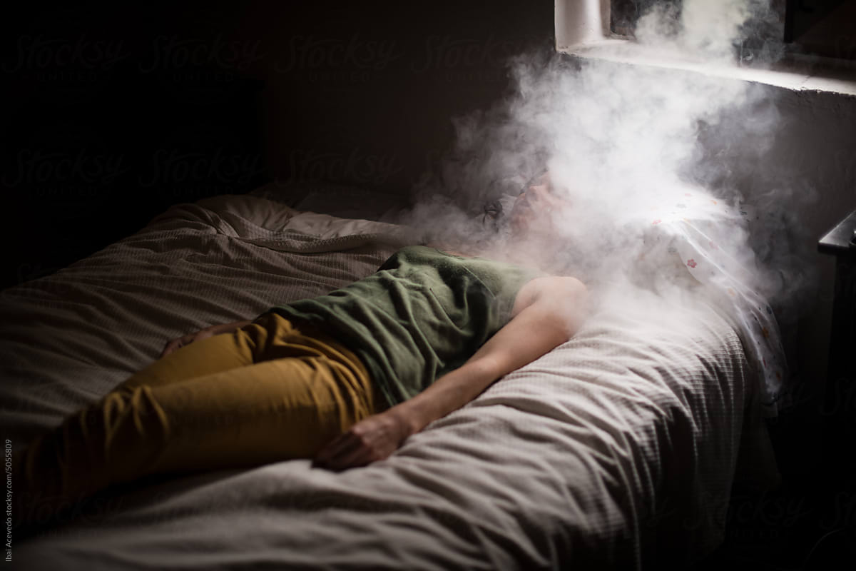 Sleeping woman with dreamlike smoke cloud on bed