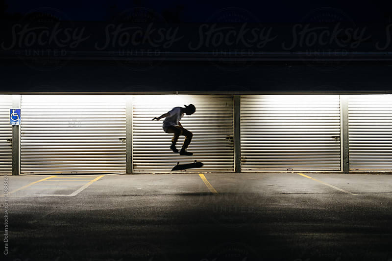 Skateboarder in a parking lot at night