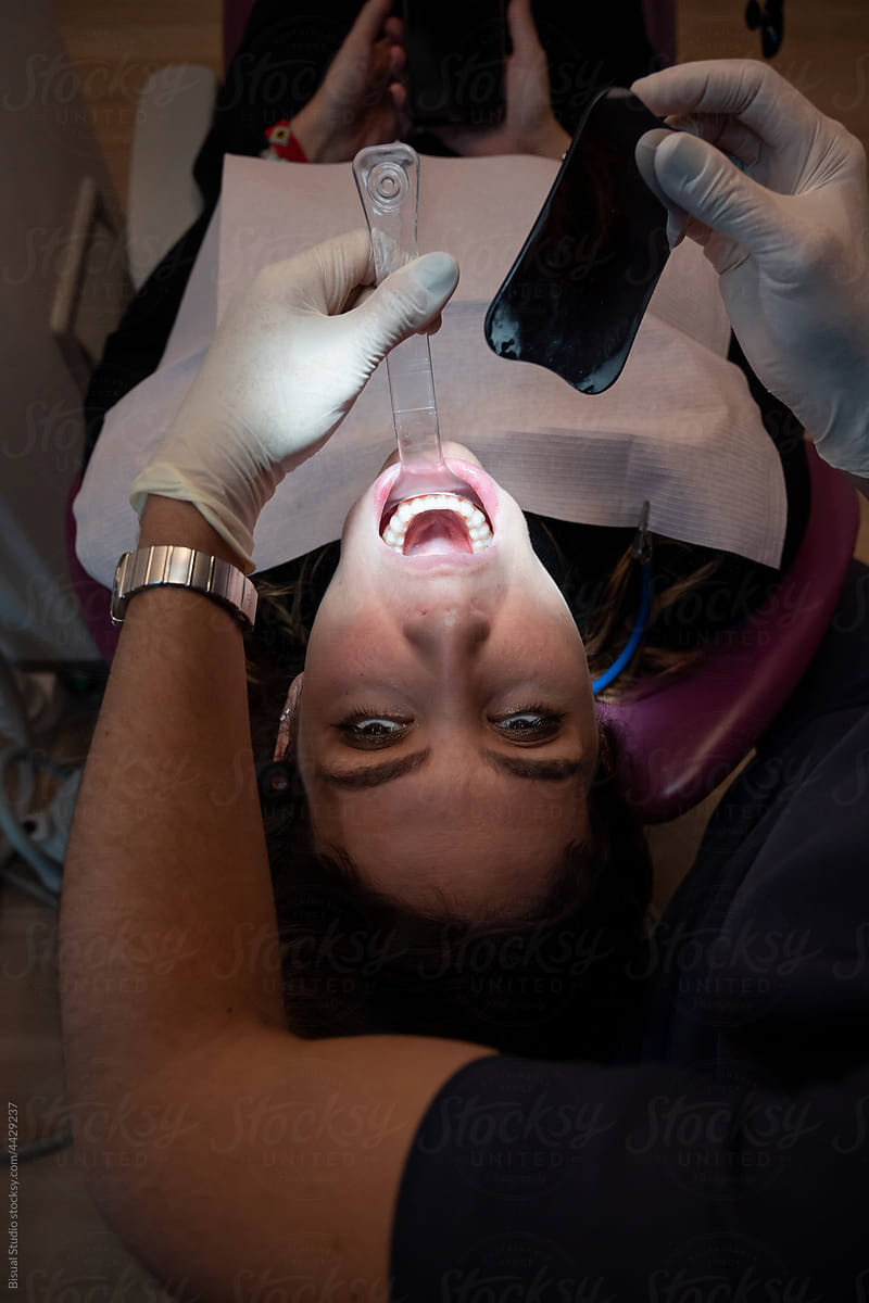 Orthodontist checking teeth of patient with mirror