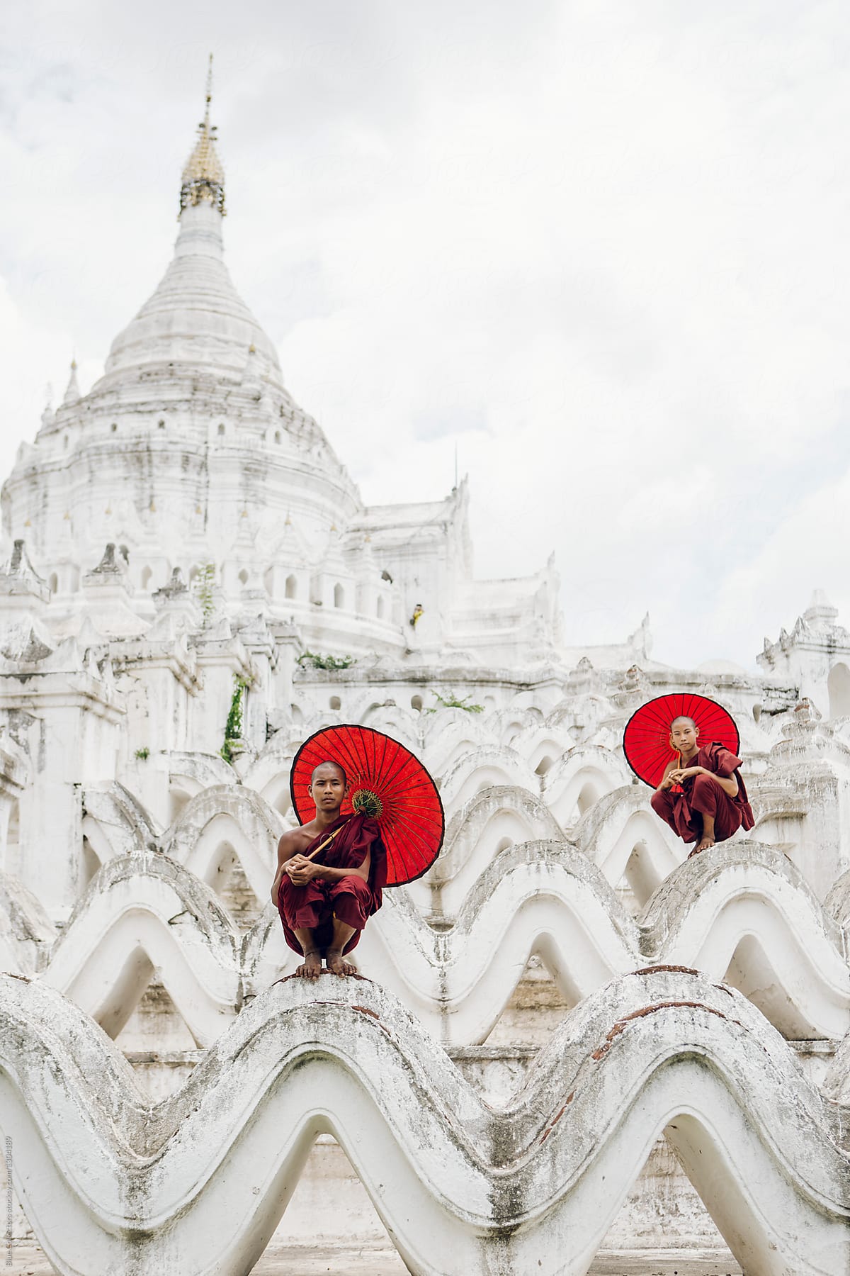 Two novice Buddhist monks with a red umbrellas in a Hsinbyume Temple