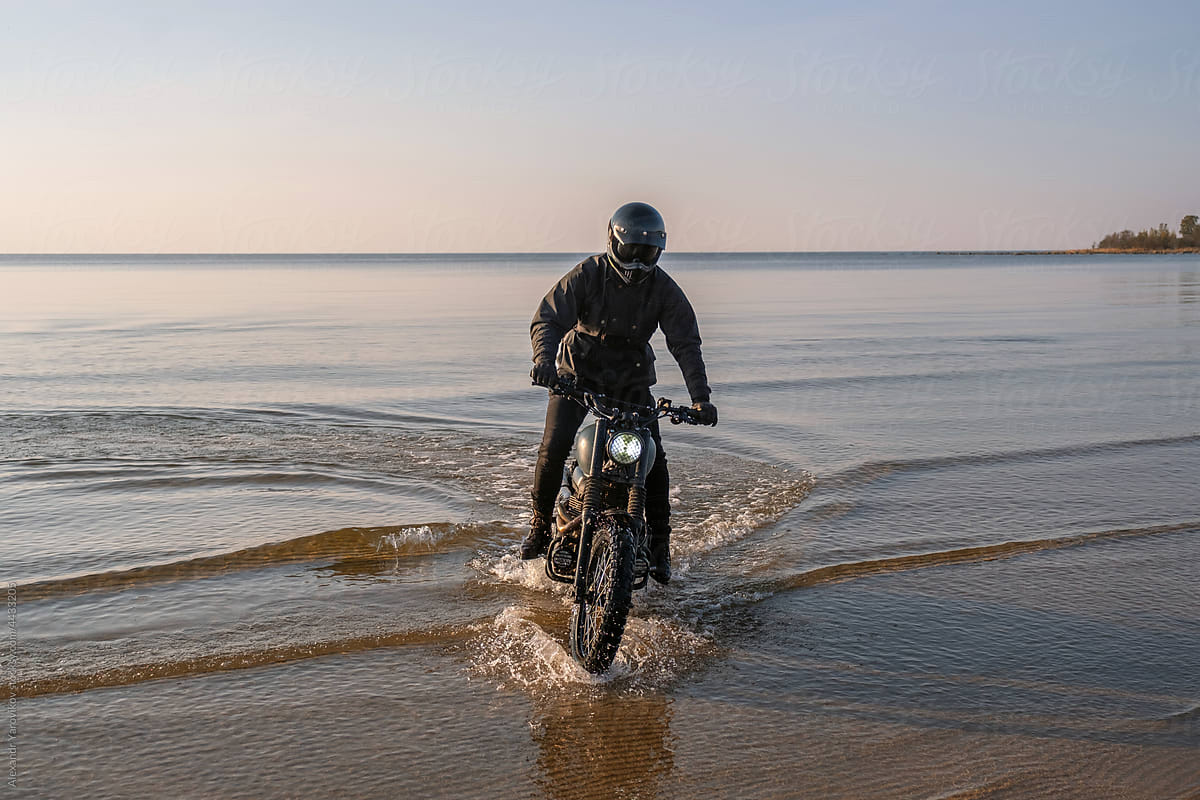 A rider on a scrambler rides out of the water