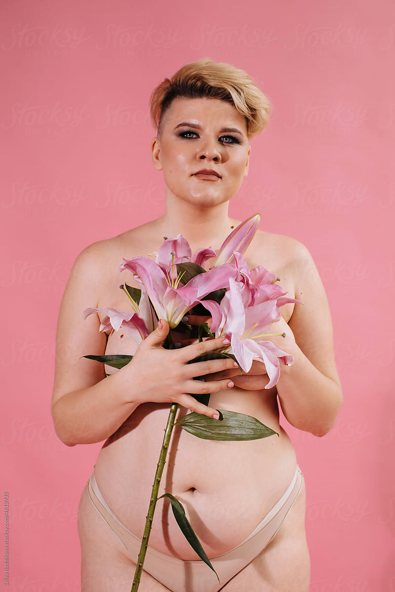 Woman with short blond hair posing with pink lilies