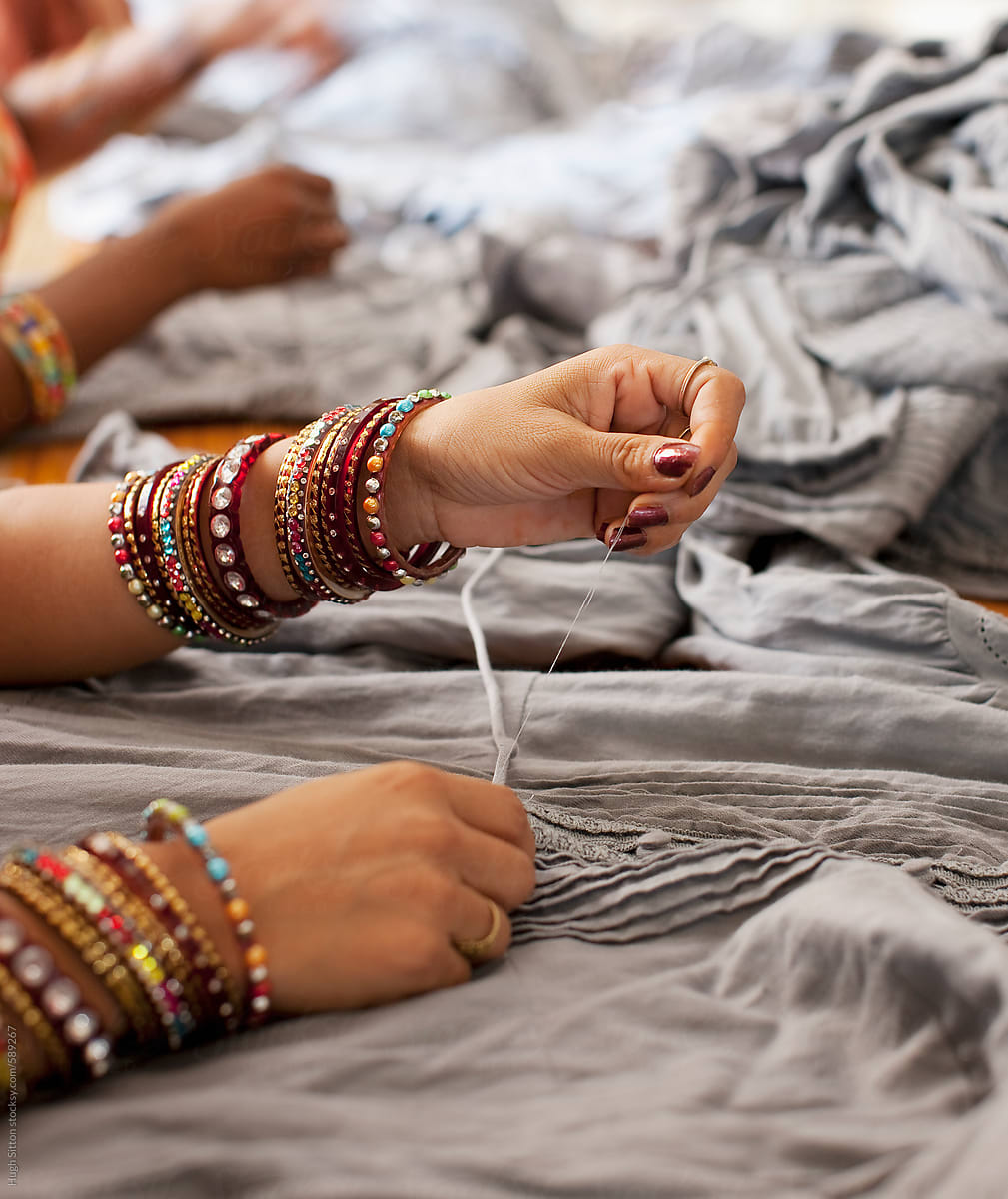 Close-up of Hindu woman sowing clothes (wearing bangles). India