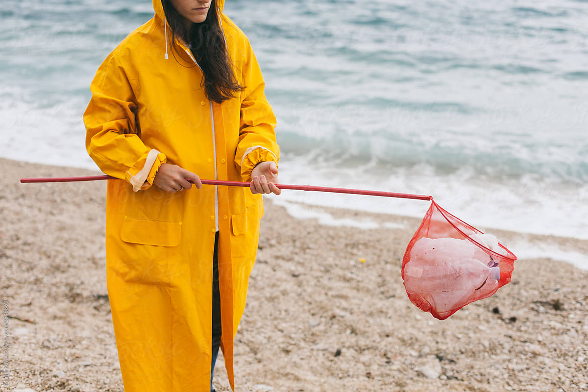 Woman cleaning up a plastic from the beach