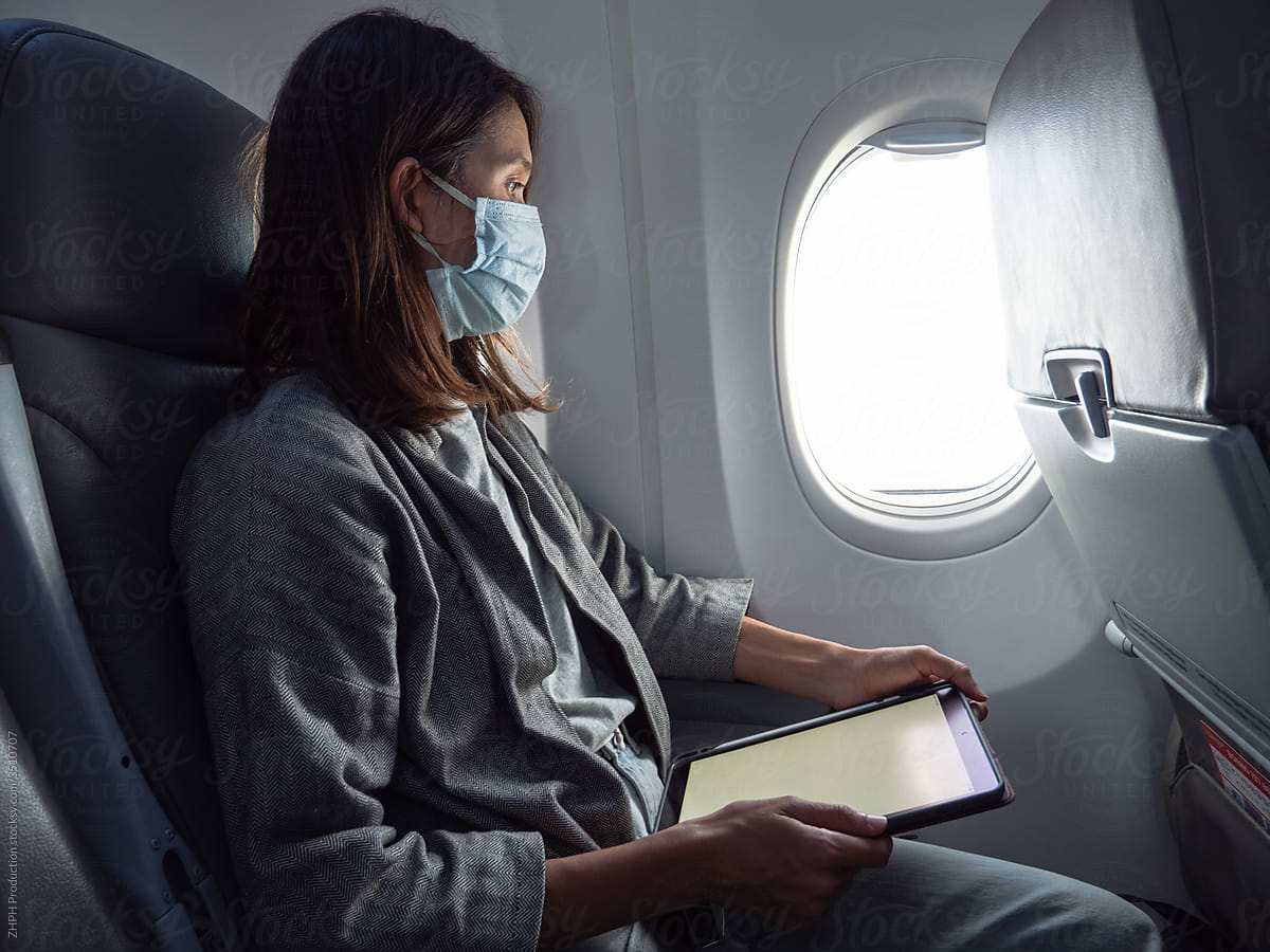 Woman wearing face mask in airplane