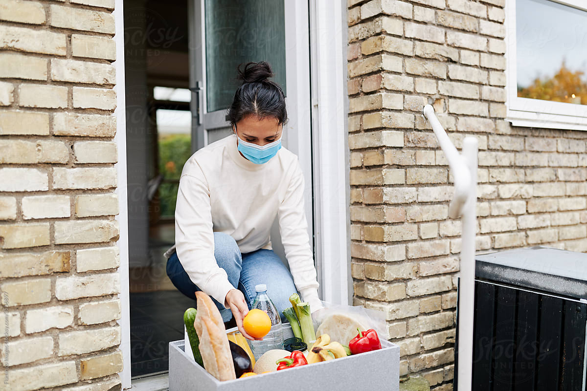 Woman in a mask receiving a grocery delivery