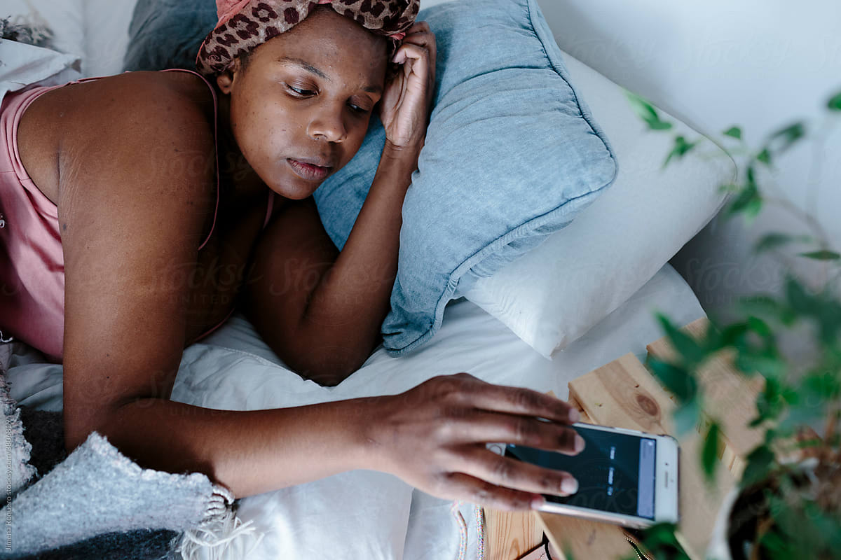 Woman in bed turning off alarm on cell phone