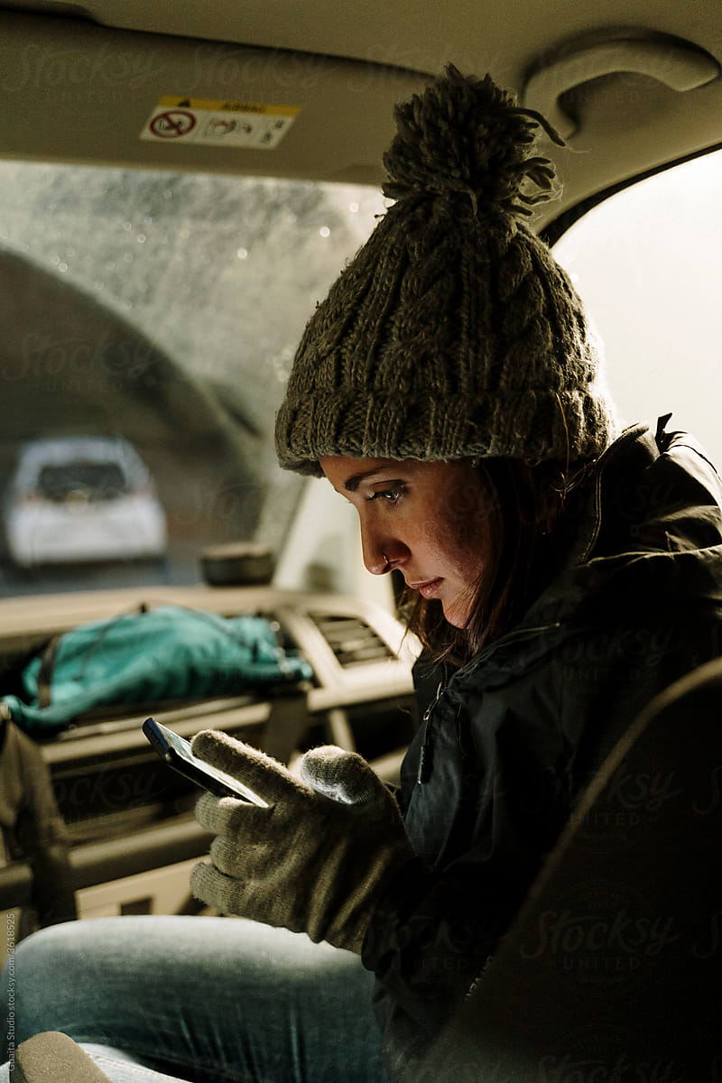 Young woman looking at phone inside car