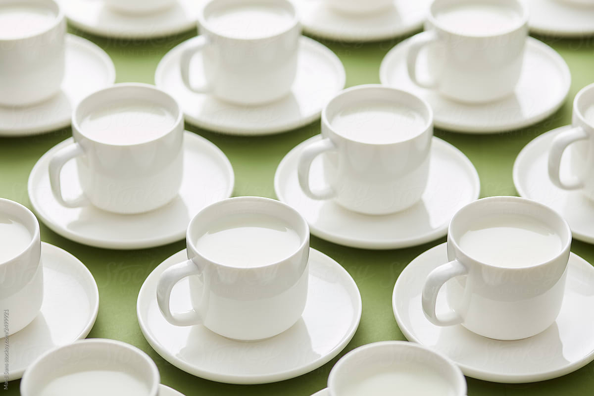 White cups of milk on green backdrop