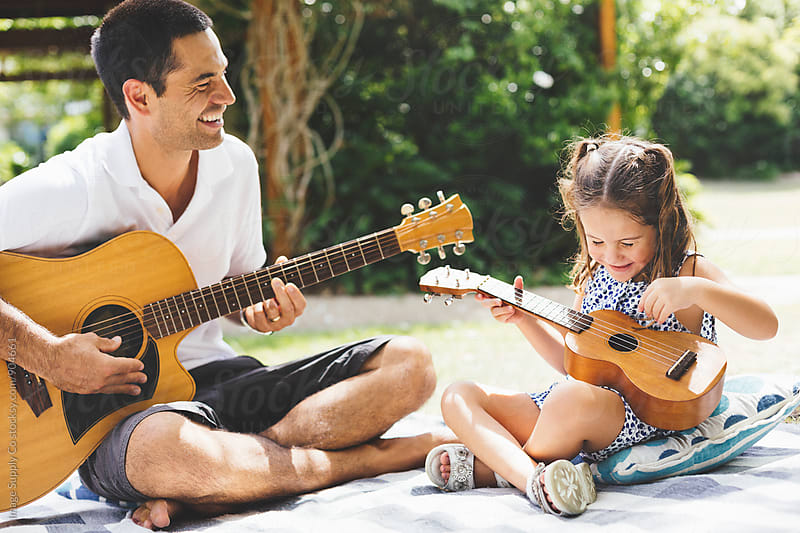 Father having a picnic with daughter and playing guitar