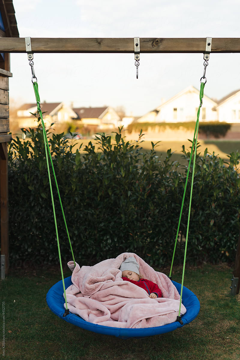 Cute toddler girl sleeping in a round swing outdoors
